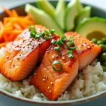 A beautifully arranged salmon bowl with seared salmon, fresh vegetables, and rice, garnished with sesame seeds and green onions