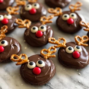 Close-up of festive chocolate christmas reindeer cookies from a delightful recipe, featuring pretzel antlers and candy eyes on a marble surface.