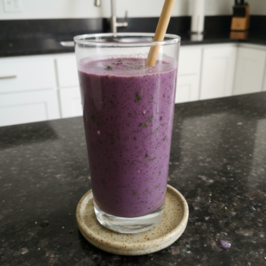 A vibrant purple Blueberry Spinach Smoothie in a tall glass, garnished with fresh blueberries and a mint leaf.