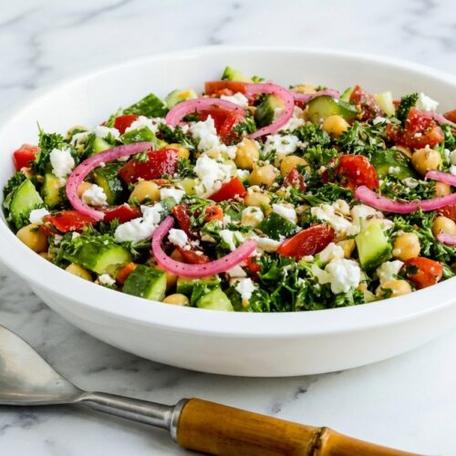 Chickpea Salad with Cucumbers and Tomatoes featuring sumac-pickled red onions and toasted cumin on white marble.