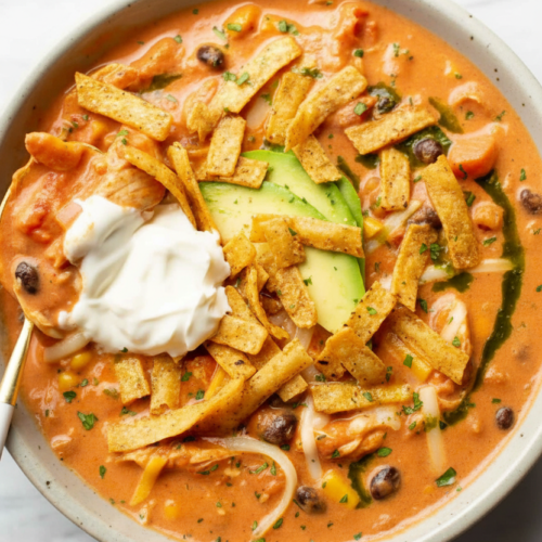Creamy chicken tortilla soup with fire-roasted charred corn and poblano infusion in a minimalist ceramic bowl on white marble.