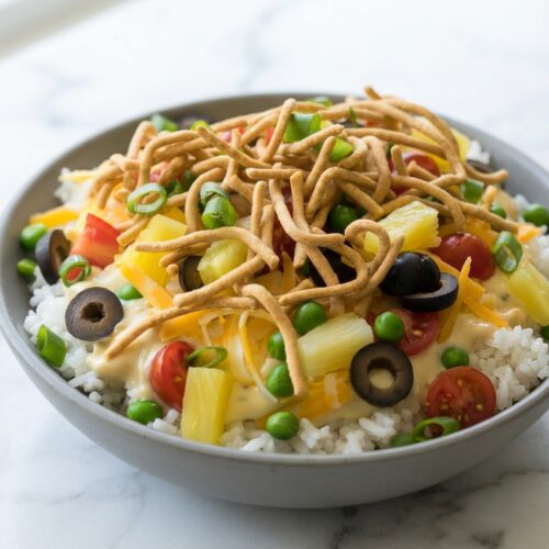 Hawaiian haystacks recipe featuring creamy chicken over a coconut-infused jasmine rice base in a white ceramic bowl.