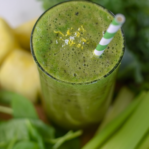 Celery Smoothie in a minimalist ceramic glass on a white marble surface, topped with lemon zest and flaky sea salt.
