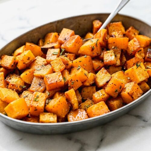 Roasted Butternut Squash on white marble with bourbon brown butter glaze and soft natural window lighting.