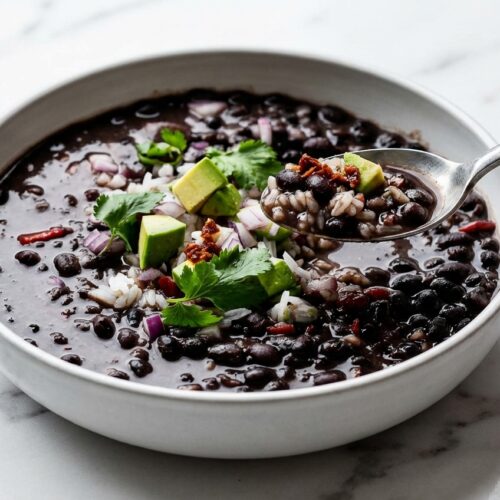 Instant Pot Black Bean Soup in a minimalist ceramic bowl on white marble, featuring a smoky chipotle pepper sofrito twist.