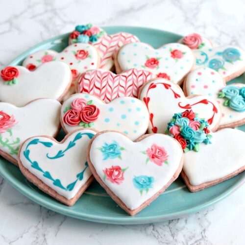 Heart-shaped valentine sugar cookies featuring strawberry-rose infused dough on a white marble surface with natural window lighting.