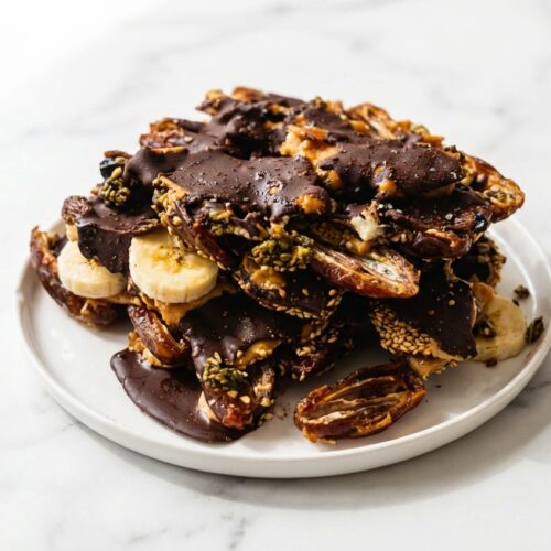 Top-down view of Banana Date Bark on white marble with espresso-infused chocolate and toasted sesame seeds.