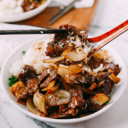 Beef Stir-Fry with Onions on white marble, glossy black vinegar deglaze finish, tender flank steak, natural window light.