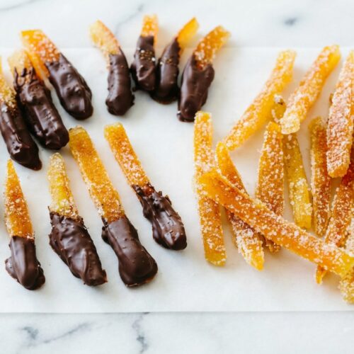Candied Orange Peel Chocolate dipped in dark tempered chocolate with a smoked sea salt and espresso infusion on white marble.