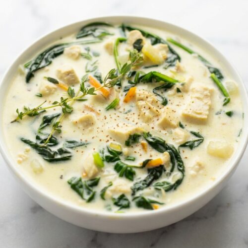 Creamy chicken gnocchi soup in a minimalist ceramic bowl on white marble, featuring a nutmeg-scented velvety broth.
