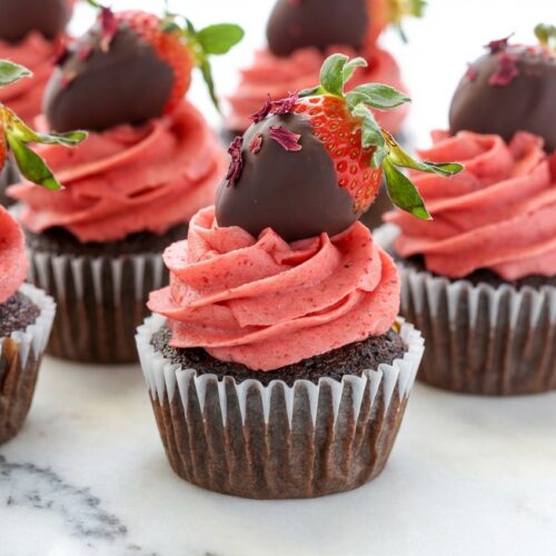 Chocolate-Covered Strawberry Cupcake on a white marble surface, showing the rich hibiscus-infused chocolate crumb and velvety frosting under natural window lighting.
