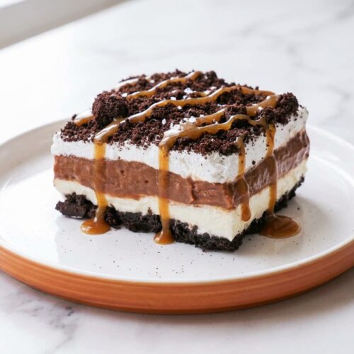 Creamy Oreo Lasagna showing dark cookie layers and espresso-salted brown butter drizzle on a white marble surface.