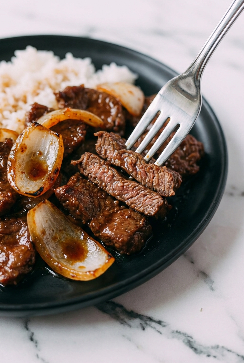 Sizzling Beef Stir-Fry with Onions in a minimalist ceramic bowl, capturing soft shadows and natural window lighting.