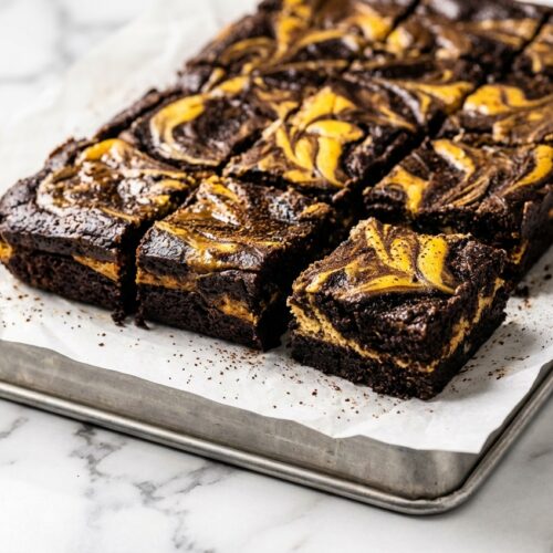 Fudgy Keto Pumpkin Brownies on a white marble surface, featuring a dense texture from brown butter and espresso.