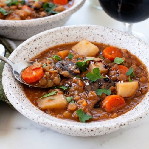 Irish vegetarian stew in a minimalist ceramic bowl on marble, finished with dark balsamic glaze and smoked sea salt.