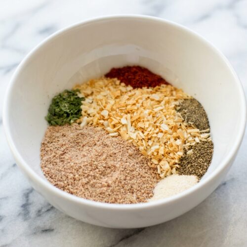 Toasted onion soup mix recipe in a minimalist ceramic bowl on a white marble surface with natural window lighting.