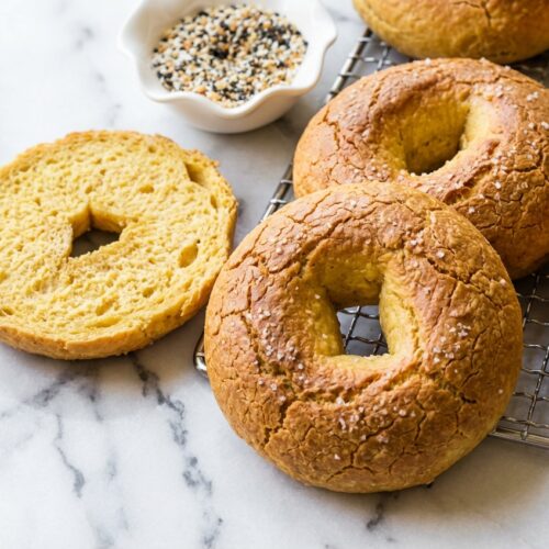 Protein Bagels with Cottage Cheese on white marble, showcasing a golden crust from the unique salt water brine spray.