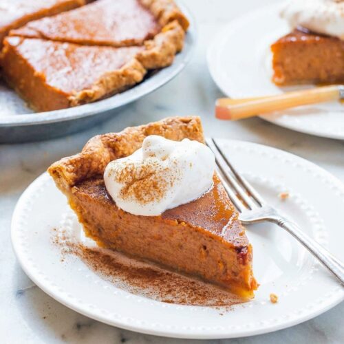 Sweet Potato Pie with brown butter and smoked bourbon infusion on a white marble surface with natural window lighting.