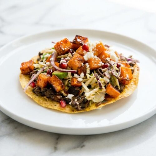 Black Bean Sweet Potato Tostadas featuring smoked paprika and honey glazed roast on a minimalist ceramic plate with soft shadows.