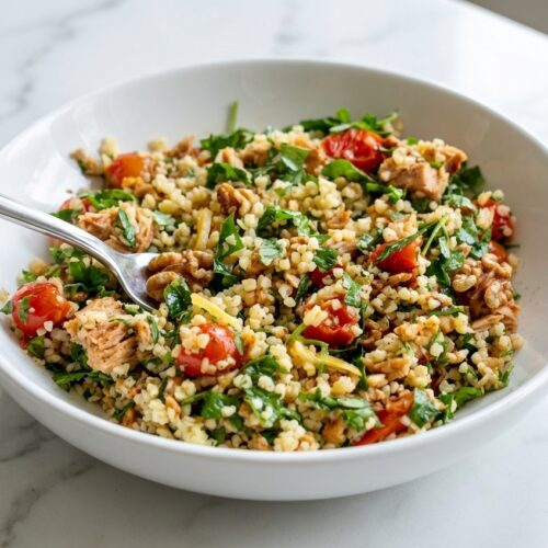 Bulgar Wheat & Tuna Mediterranean Salad with toasted walnuts and preserved lemon on a minimalist ceramic plate over white marble.