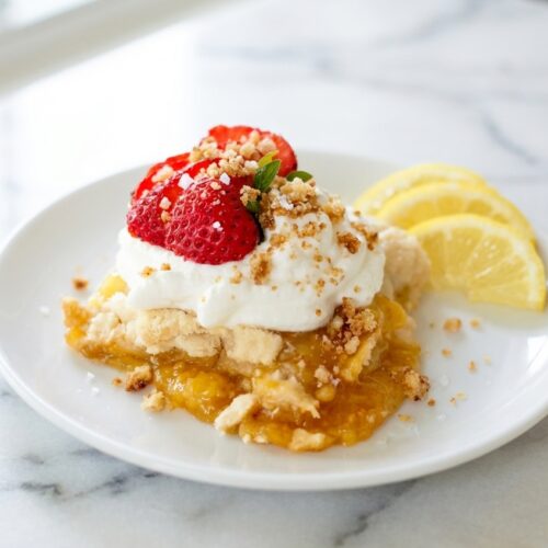 Buttery Lemon Dump Cake with a brown butter sea salt crumb on a white marble surface in natural window lighting.