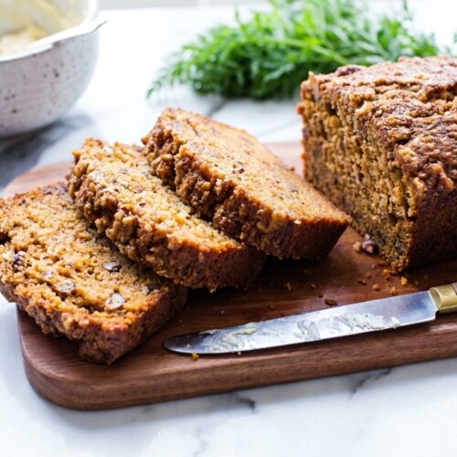 Carrot Cake Bread with a golden brown butter and ground walnut crust on a white marble surface with natural lighting.