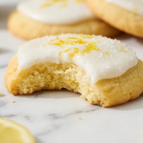Cheerful Lemon Cookies featuring a glistening lemon-sugar infusion on a white marble surface with soft natural lighting.