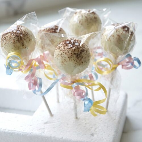Close-up of Classic Cake Pops with salted espresso glaze on a white marble surface under natural window lighting.