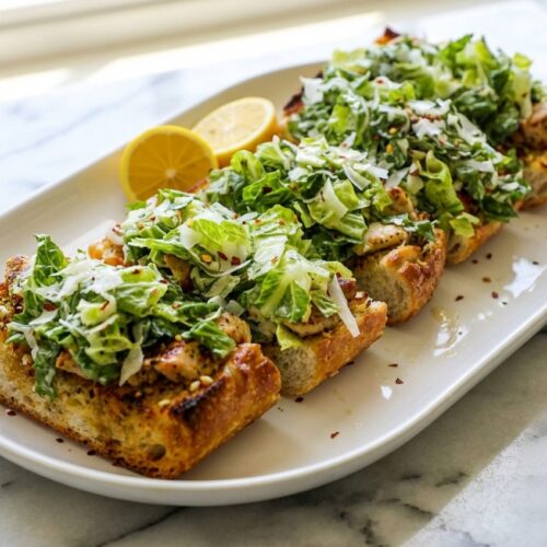 Garlic Bread Chicken Caesar Sandwiches with a brown butter and anchovy garlic crust on a white marble surface.
