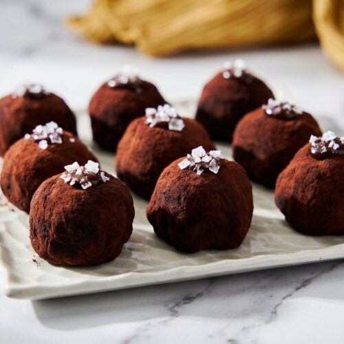 Japanese Chocolate Mochi dusted with cocoa on a white marble surface, featuring an espresso and sea salt ganache center.