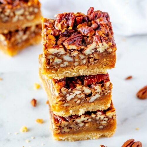 Keto Pecan Square Recipe featuring browned butter filling and crunchy pecans on a white marble surface in natural light.