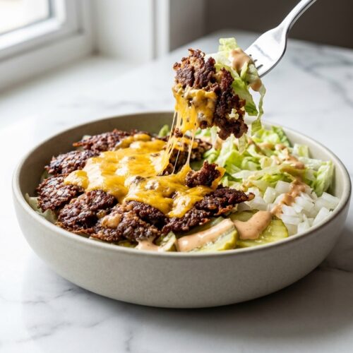 Hero shot of a Smash Burger Bowl with crispy lacey edge beef in a minimalist ceramic vessel on white marble.