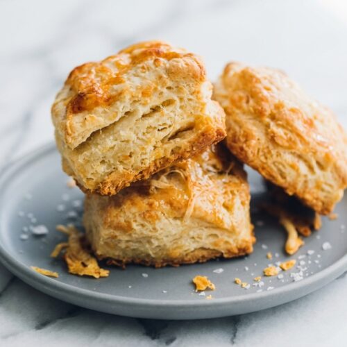 Flaky Sourdough Discard Biscuits with a brown butter honey-wash finish on white marble in natural window lighting.