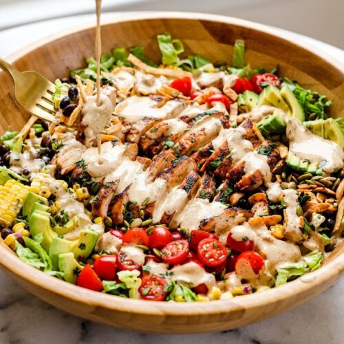 Vibrant Southwest Chicken Salad topped with Chili-Lime Toasted Pepita Crunch on a white marble surface, flat lay composition.