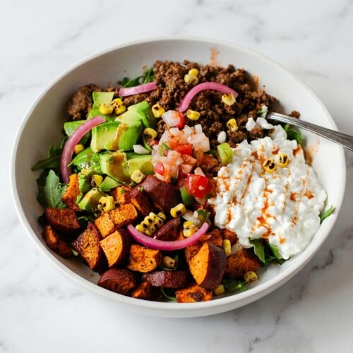 Spicy Cottage Cheese Taco Bowls in a minimalist ceramic vessel on white marble, topped with charred corn and pickled red onions.