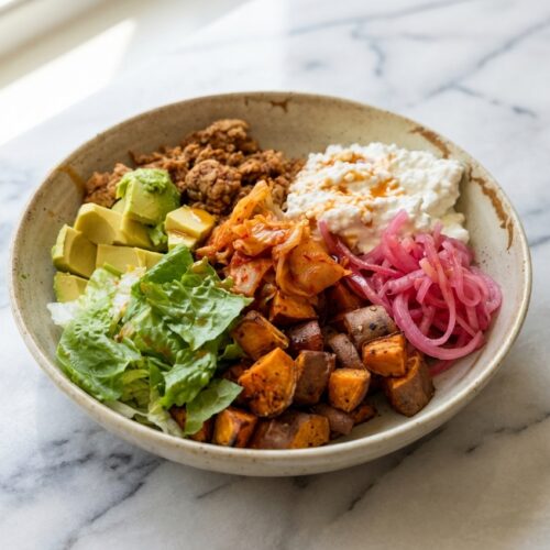 Sweet Potato Cottage Cheese Taco Bowls topped with airy whipped chipotle-lime cottage cheese on a white marble surface.
