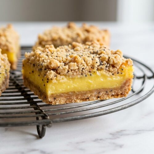 Zesty Lemon Crumb Bars on white marble with a golden ginger and poppy seed oat crumble topping.